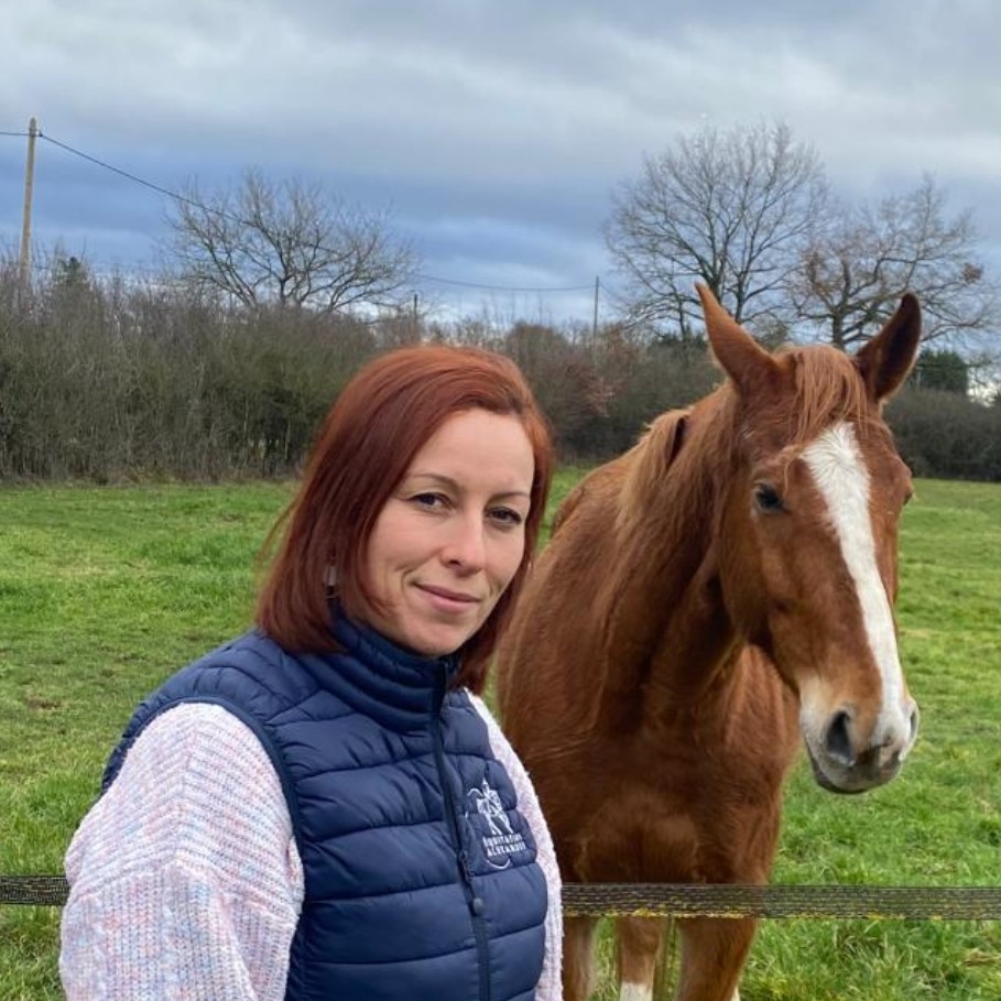 Photo de Julie, chargée de l’entretien et du bien-être des chevaux, devant un cheval